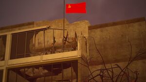 Communist insurgent seen raising a hammer and sickle flag on top of a destroyed office building.